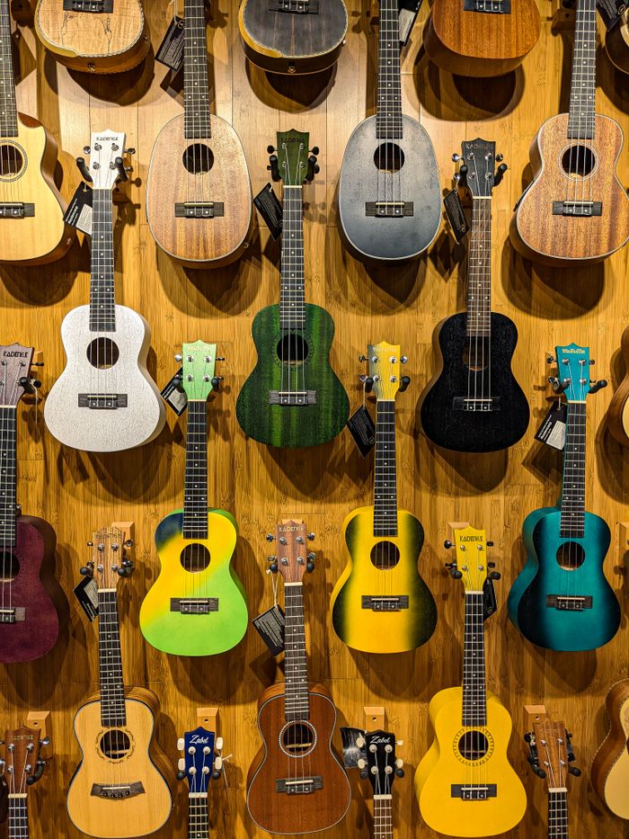 Vibrant ukuleles in various colors hanging on a wooden wall, showcasing musical diversity.