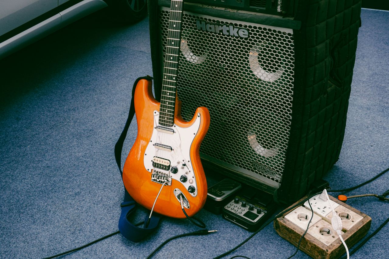 Orange electric guitar leaning against Hartke amplifier outdoors, showcasing music equipment setup.